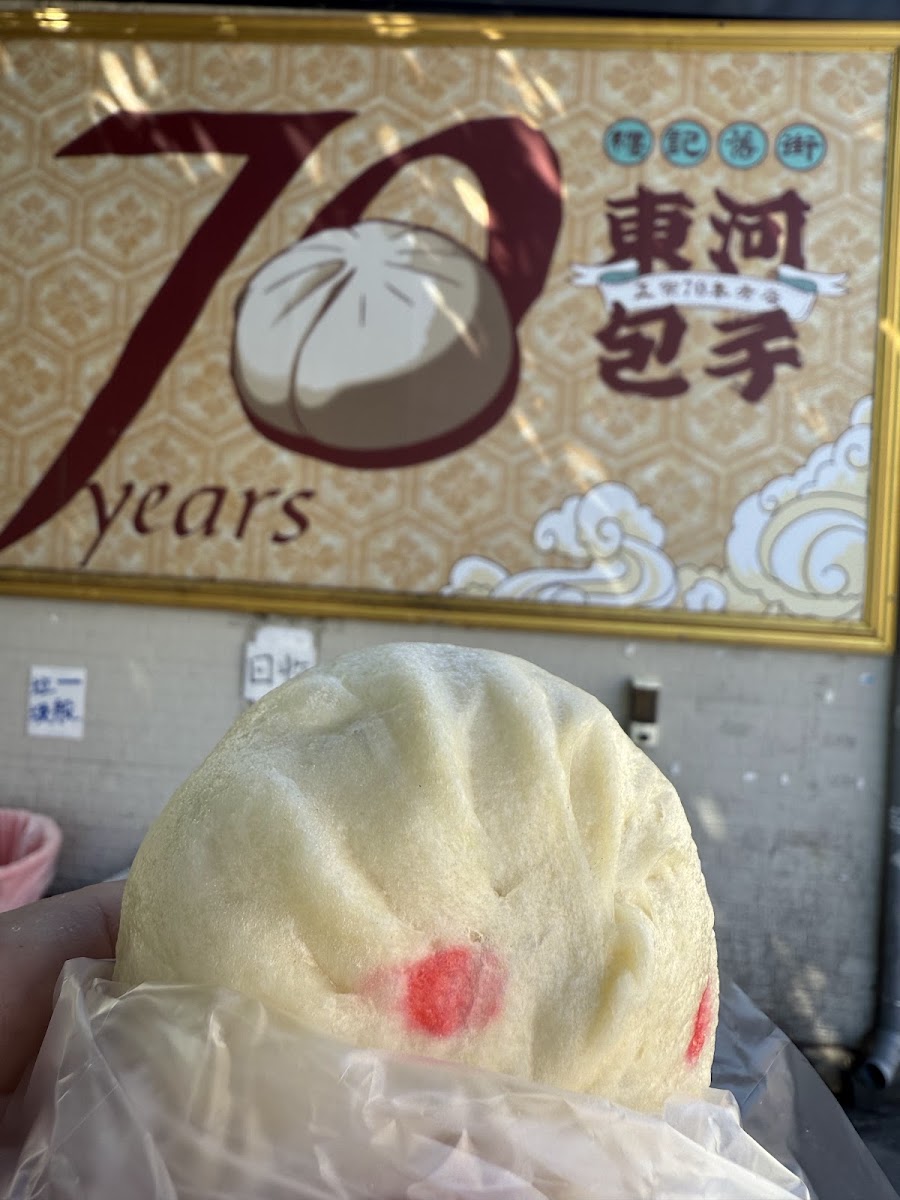 纏記舊街東河包子戶外用餐區，大榕樹遮蔭，木製桌椅，藍色吧台造景