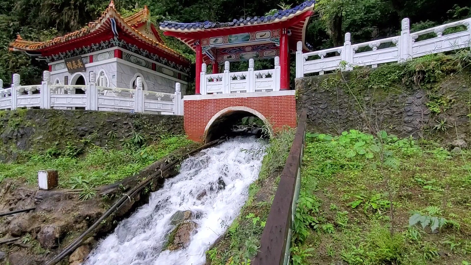 長春祠側面，峽谷瀑布從山壁傾瀉而下，白色水流與翠綠山壁形成對比