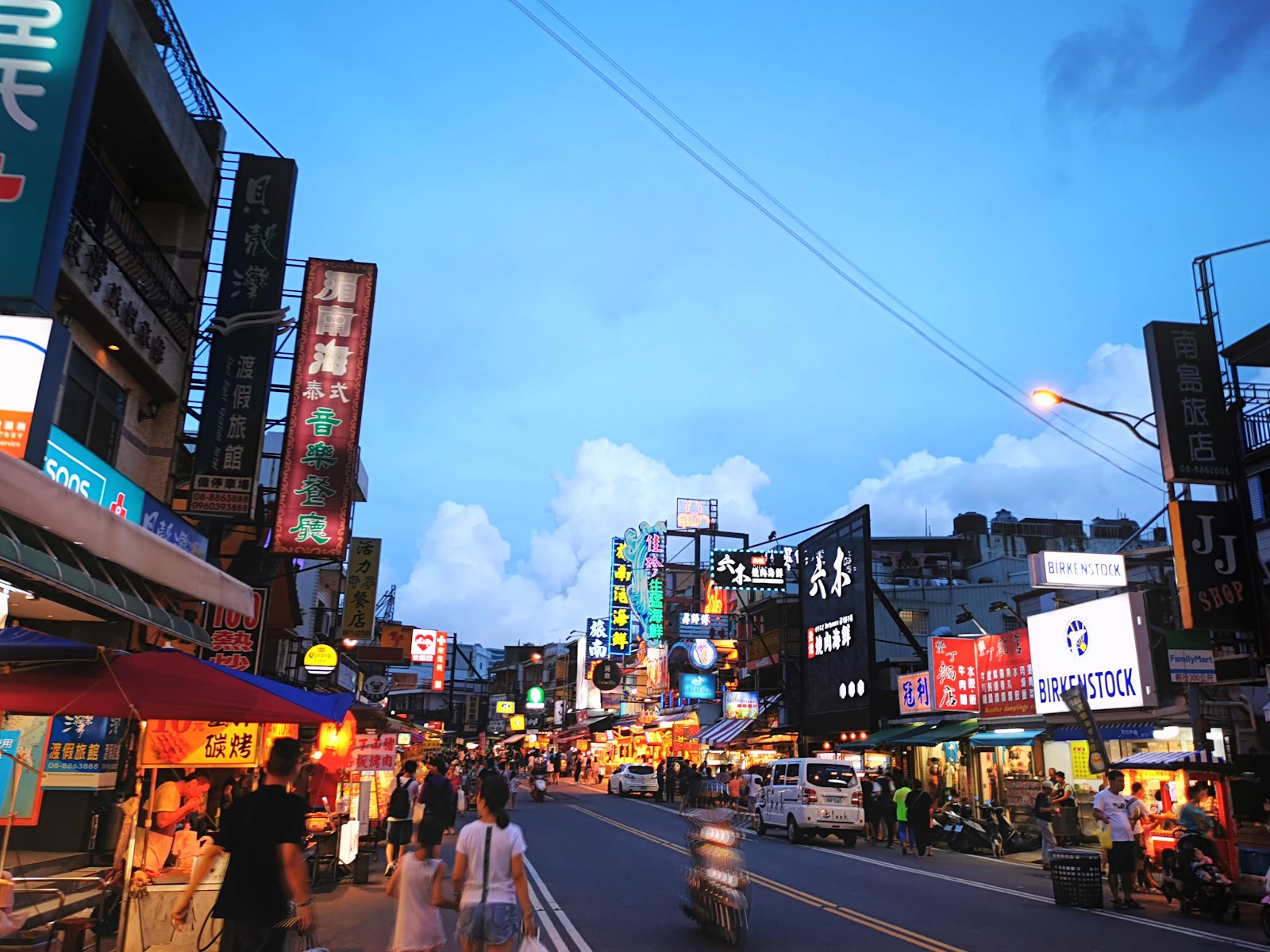 入夜後的墾丁大街，五彩霓虹招牌林立，人潮洶湧，夜市氛圍熱鬧非凡