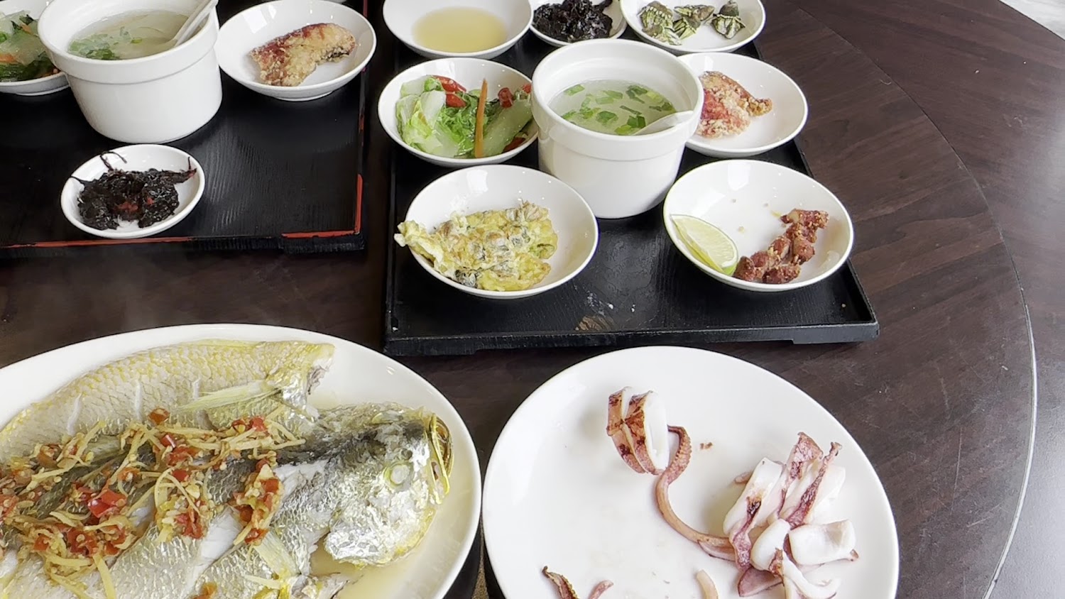 依嬤的店豐盛海鮮桌菜，有清蒸魚、烤花枝、湯品與多種小菜