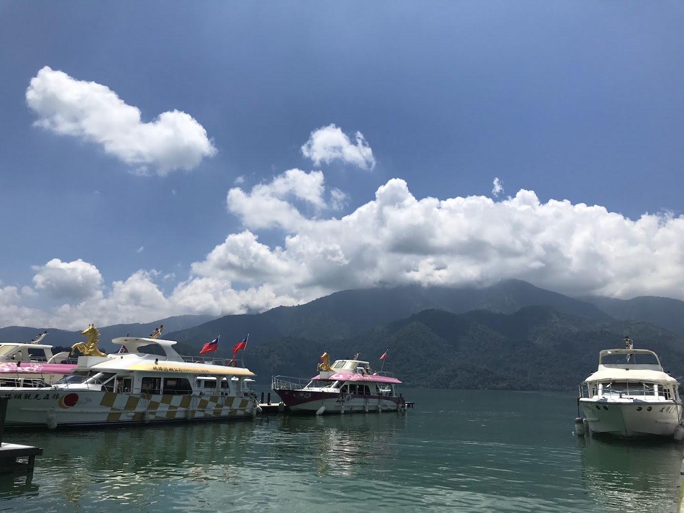 幾艘遊艇停靠在湖邊與翠綠山脈藍天白雲