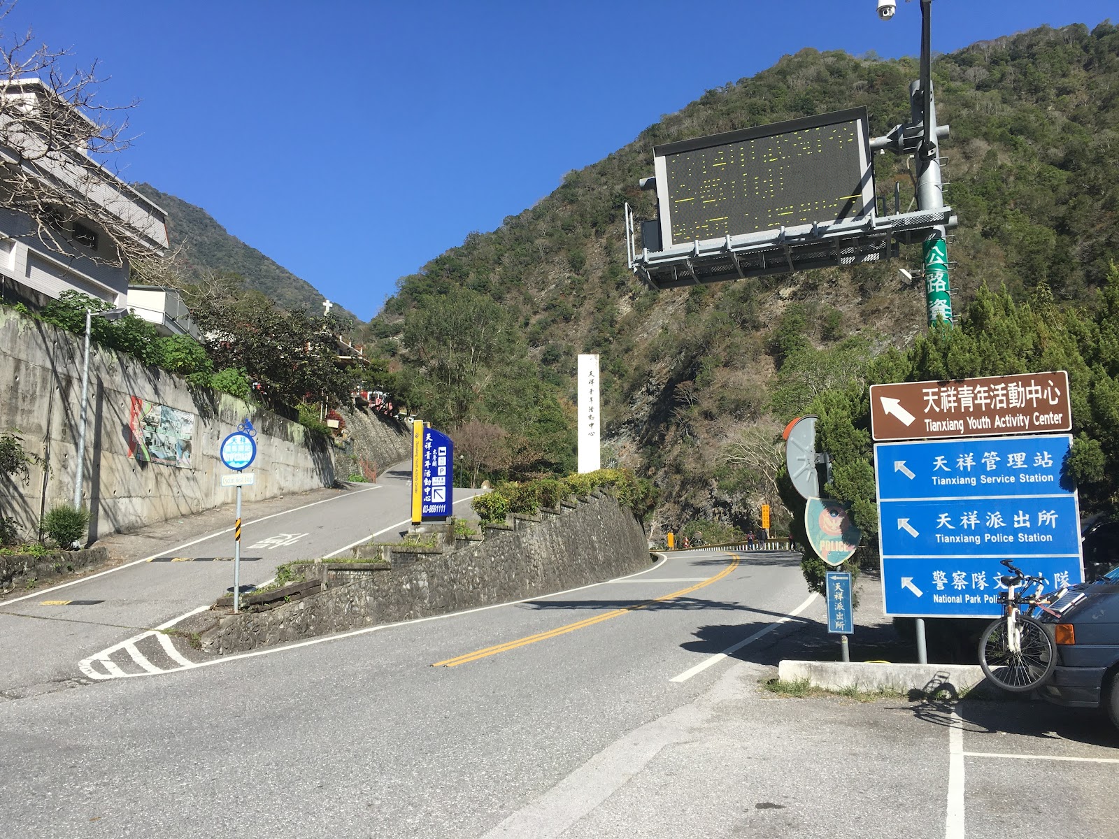 天祥遊客中心路口，路標指向天祥管理站、派出所等設施，背景青山藍天