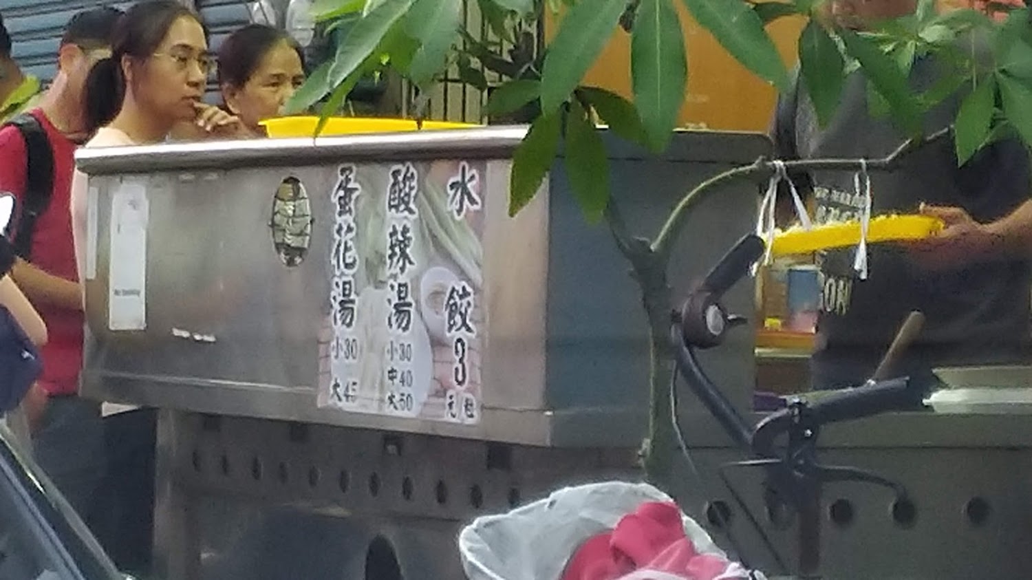 路邊攤位前有顧客排隊購買水餃與湯品