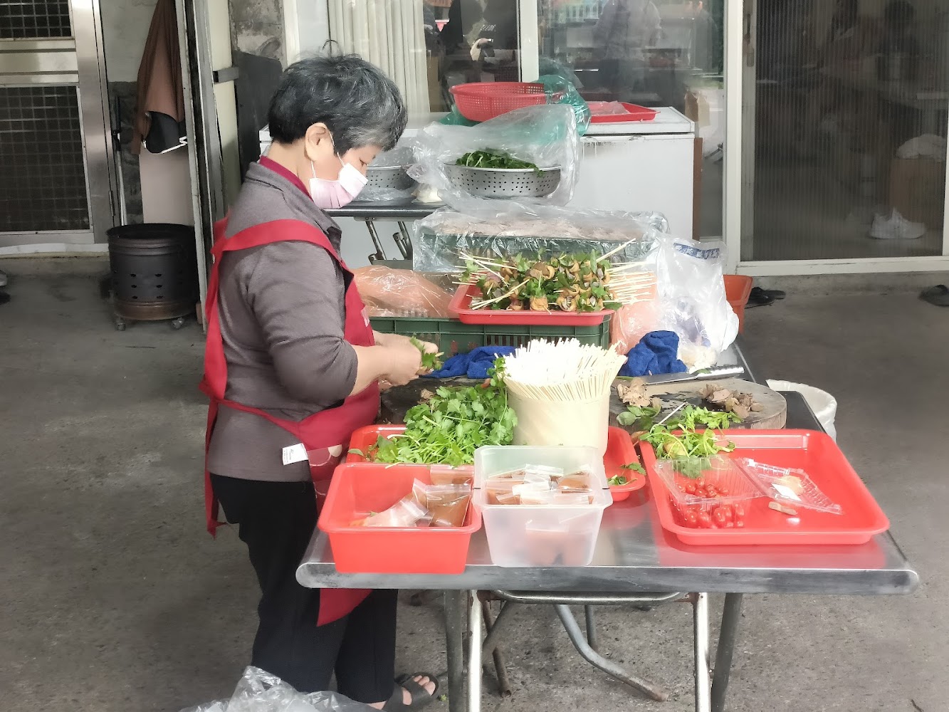 穿紅圍裙的女性正在準備攤位食材