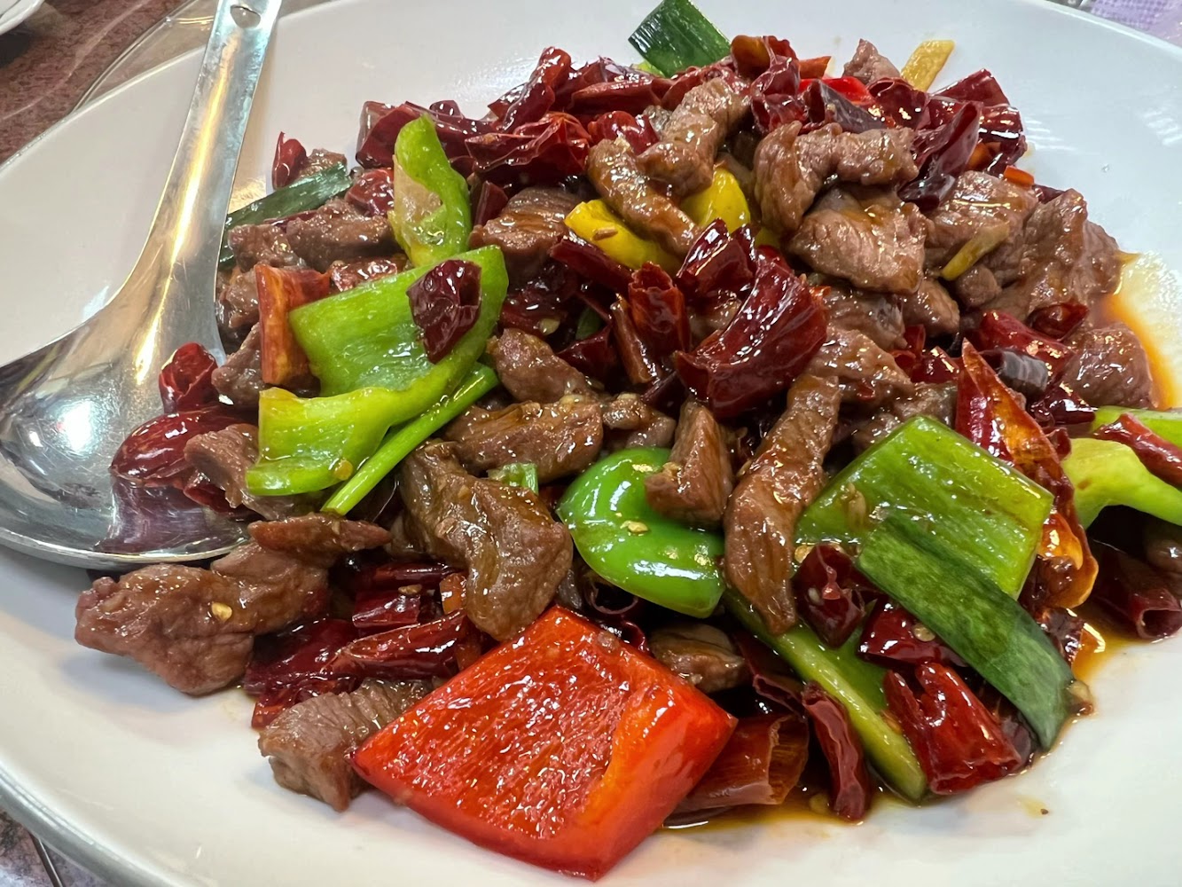 一盤辣椒炒牛肉，裡面有牛肉塊、乾辣椒，以及青椒和紅椒等蔬菜