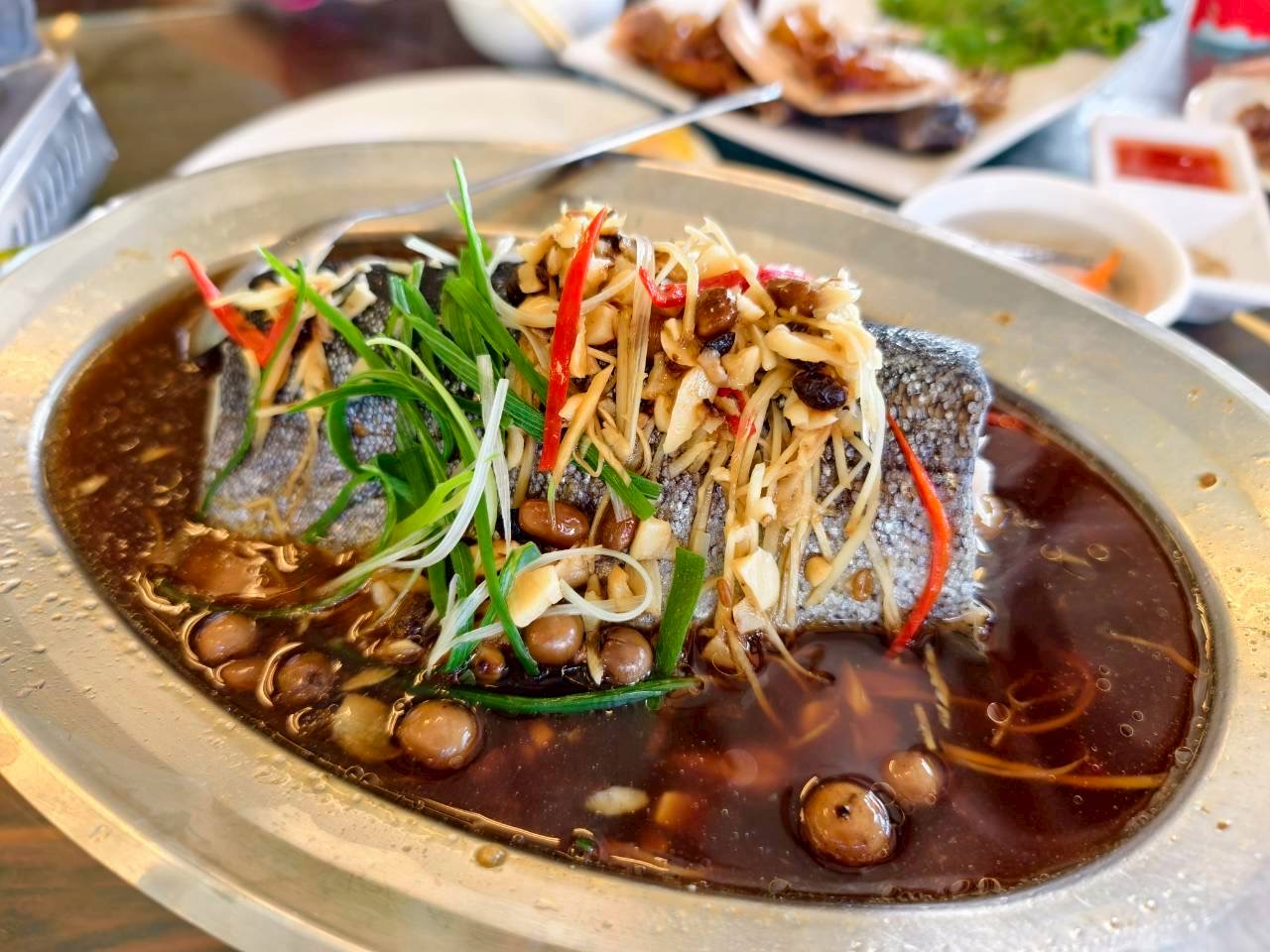 一道清蒸魚，鋪滿薑絲、青蔥、辣椒與豆豉