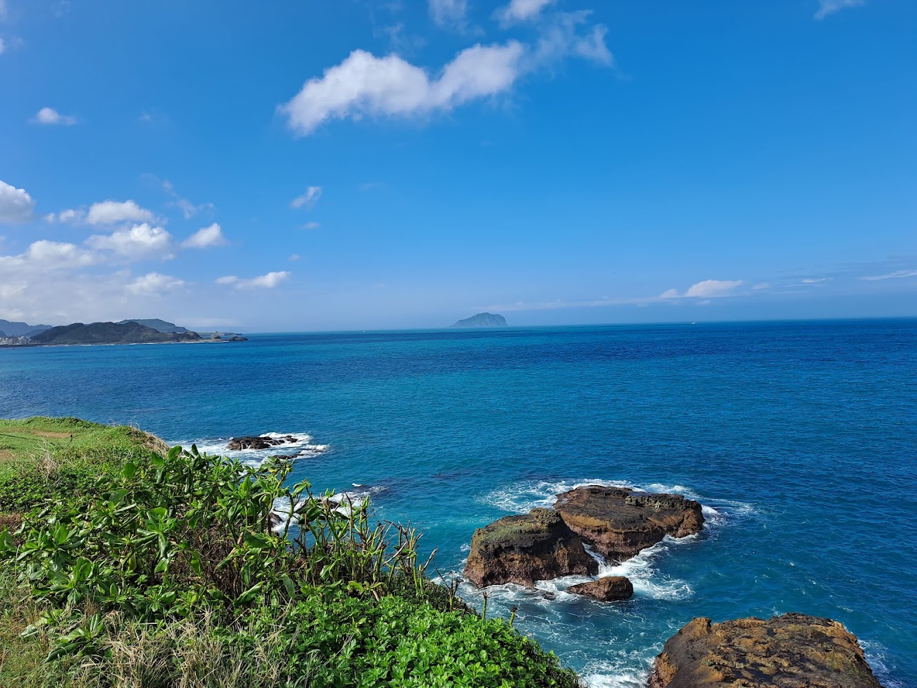 藍天白雲下的海岸觀景平台可遠望海灣與山景