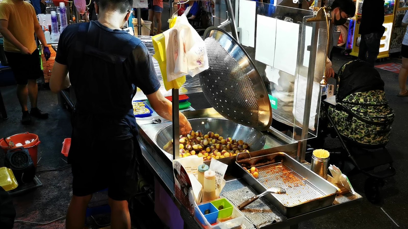 逢甲夜市攤主現炒小圓球零食，熱氣蒸騰，顧客圍觀等候