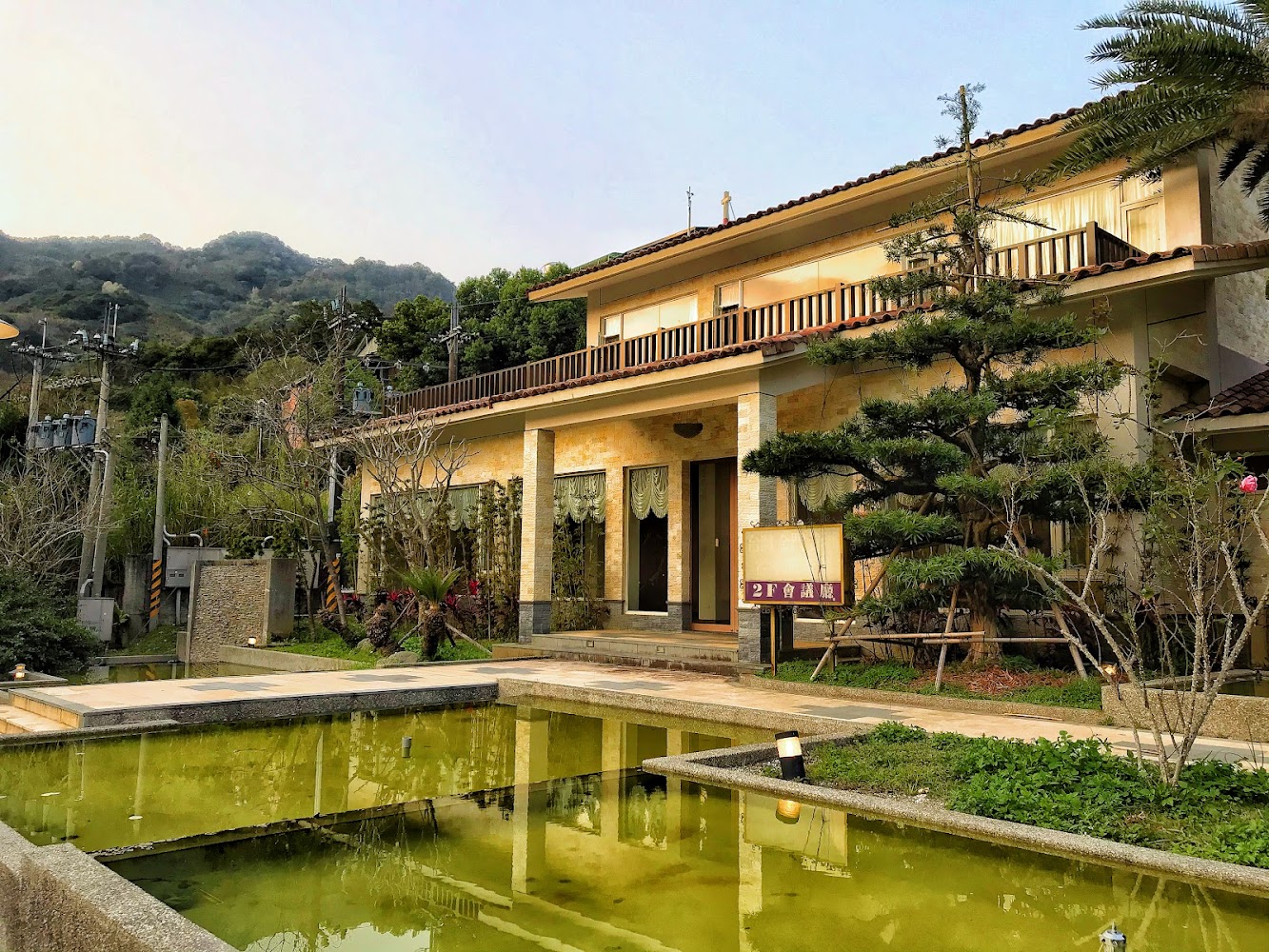 日式風格建築前有長形水池與整齊植栽