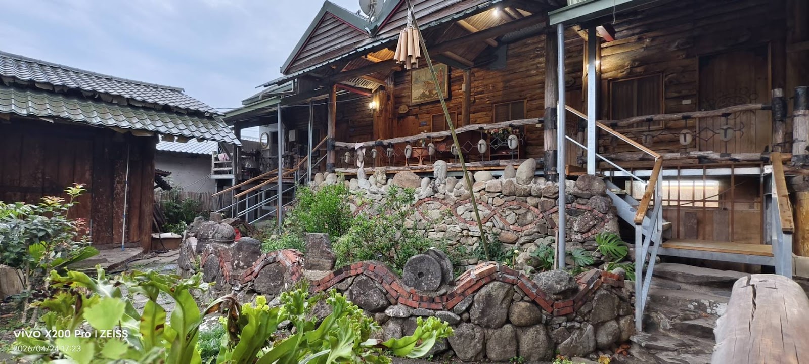 茶山部落野摩居民宿，原木石砌牆外觀，風鈴掛飾，熱帶植物環繞