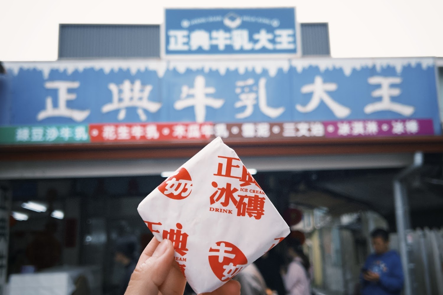 手持冰磚與店面背景