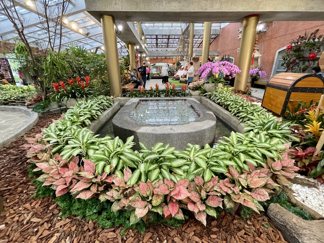 室內花園景觀有精美水池，四周環繞各色植物花卉與人工寶箱裝飾