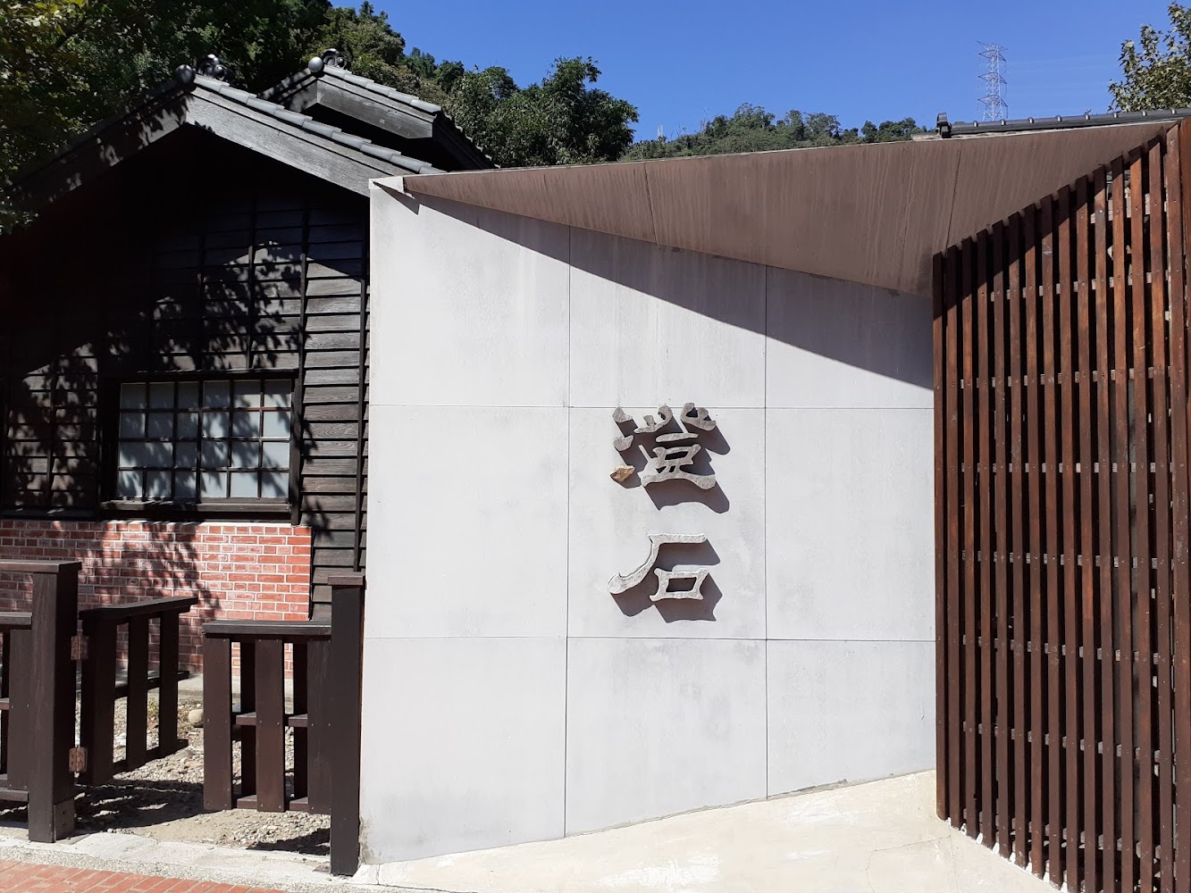 寫有蜜石二字的牆面旁有日式木造建築與柵欄