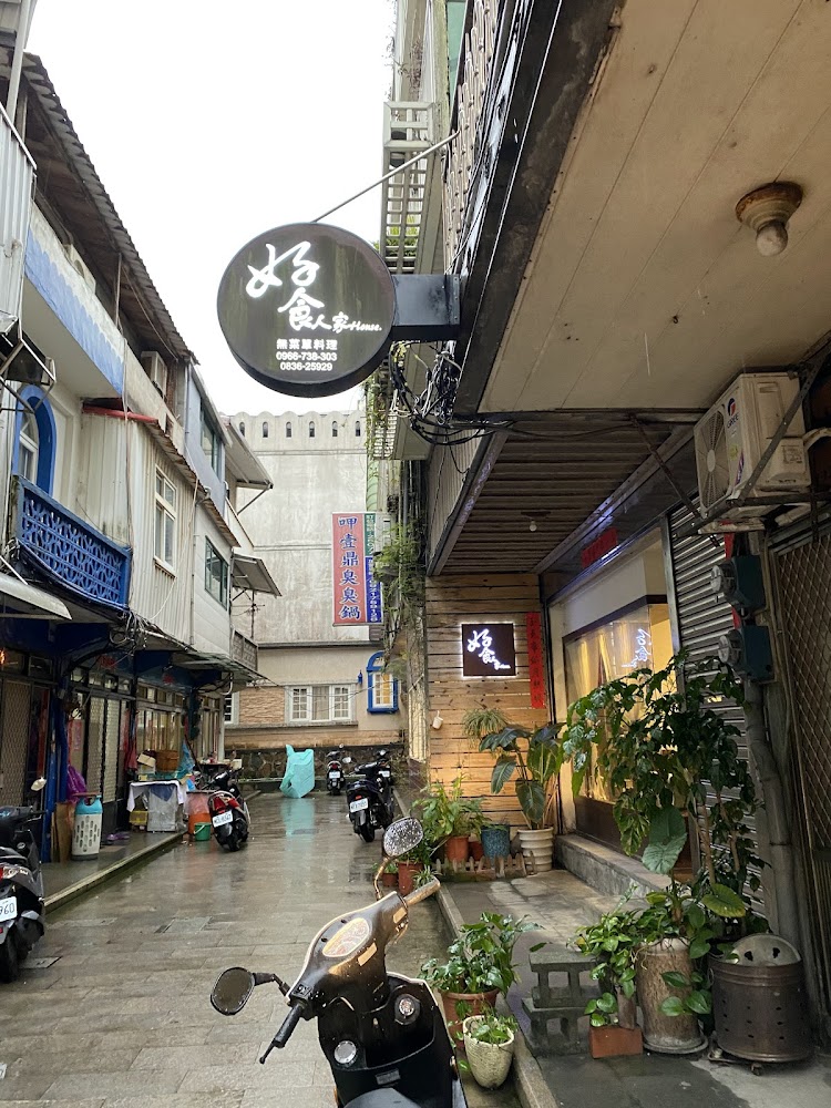 這張圖片是一條台灣巷弄，巷內有多台機車停放，左右兩旁是各式店家、招牌與綠色植物，展現出在地生活氛圍與小巷特色。