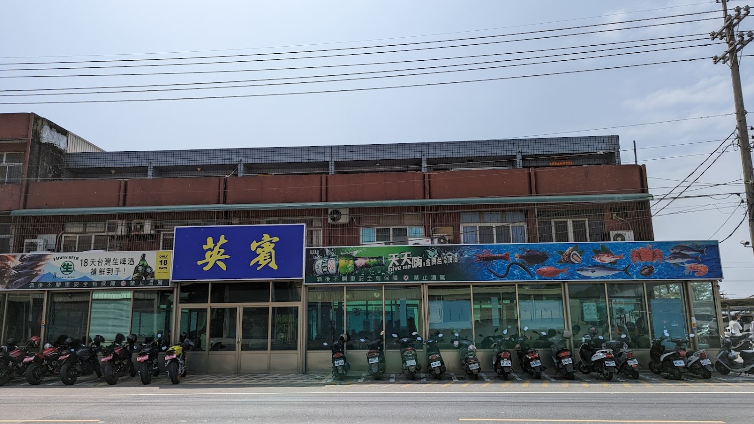 街道旁海鮮餐廳外觀，牆面有魚與螃蟹彩繪，招牌醒目