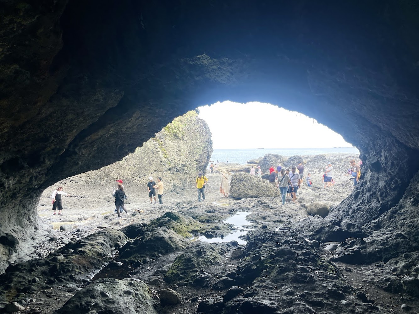 海蝕洞口外可見遊客與海景