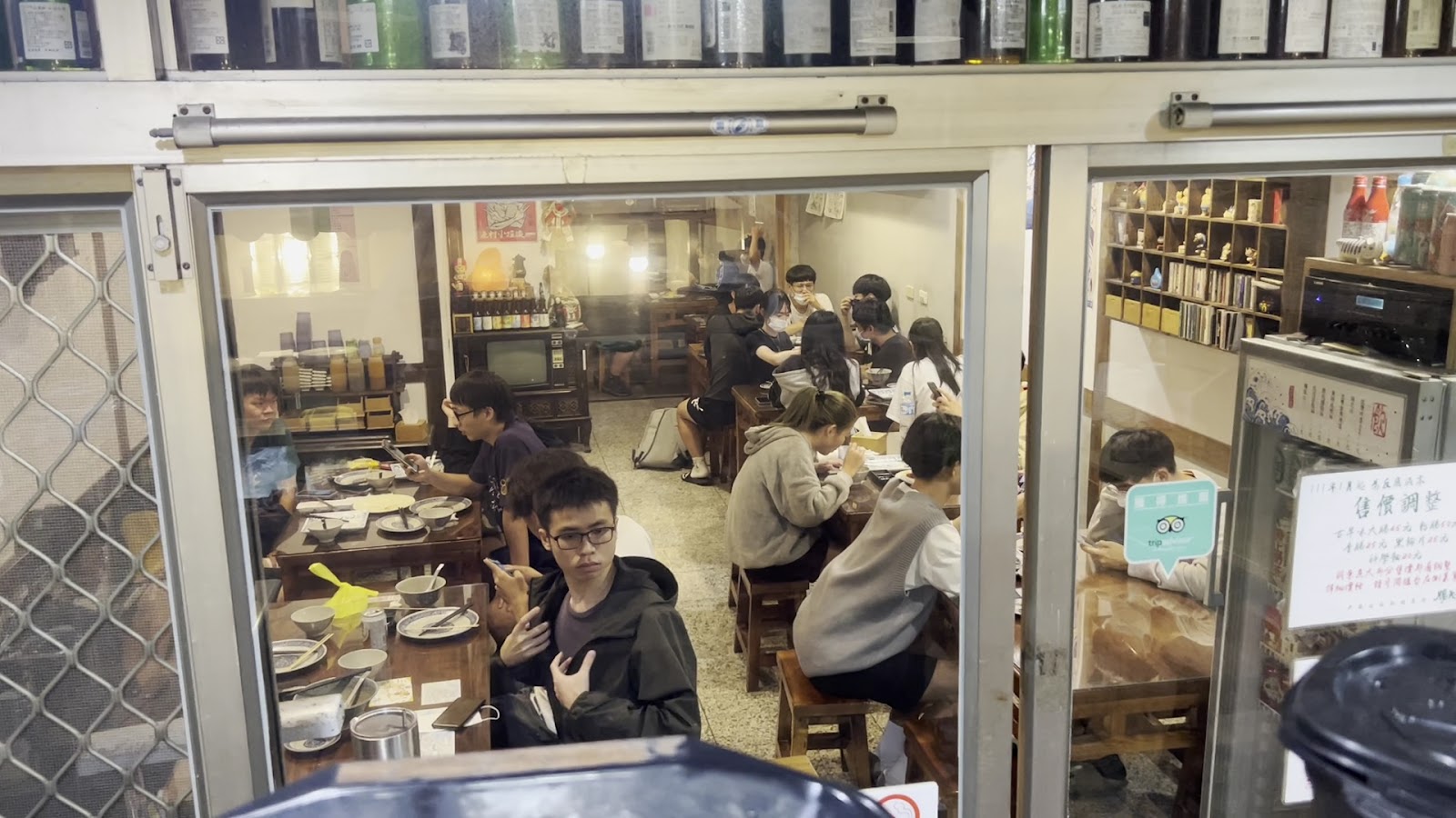 腸大爺店內用餐氛圍，日式復古暖燈，顧客在玻璃門後圍桌而坐