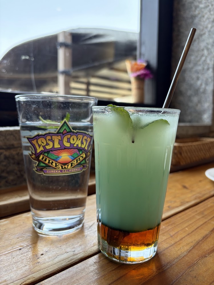 木桌上有兩杯飲料，一杯水一杯分層調酒
