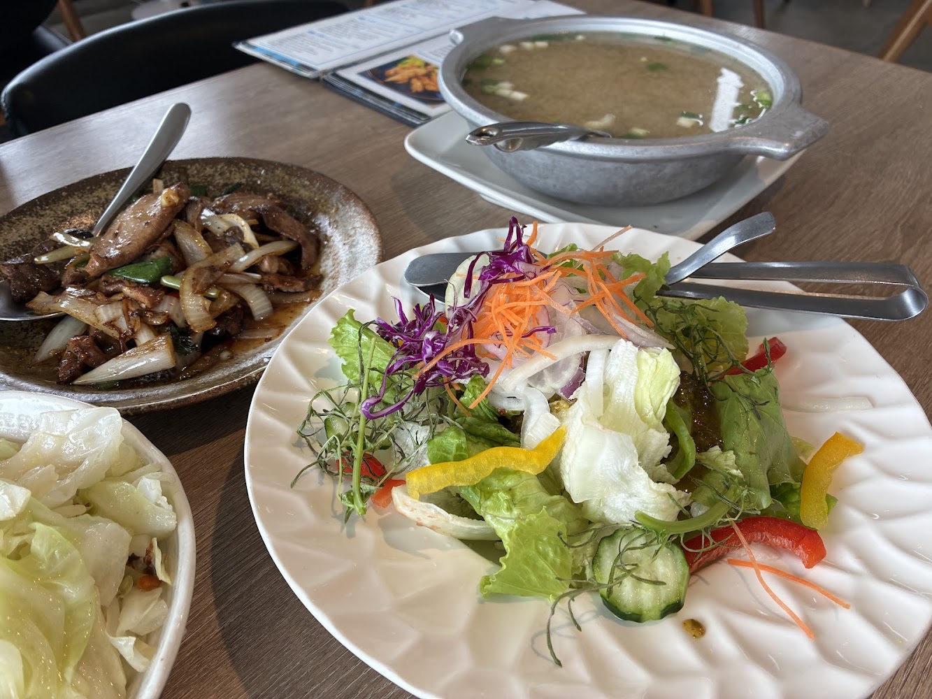 一桌豐盛餐點包含沙拉炒洋蔥牛肉與味增湯
