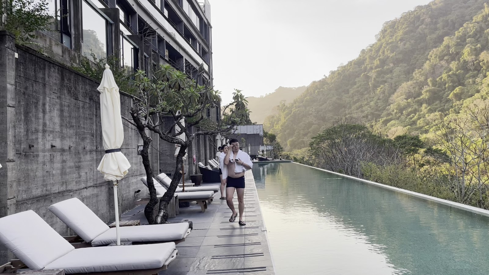 泰安觀止溫泉會館戶外無邊際泳池，旅客漫步池邊，背景翠綠山谷