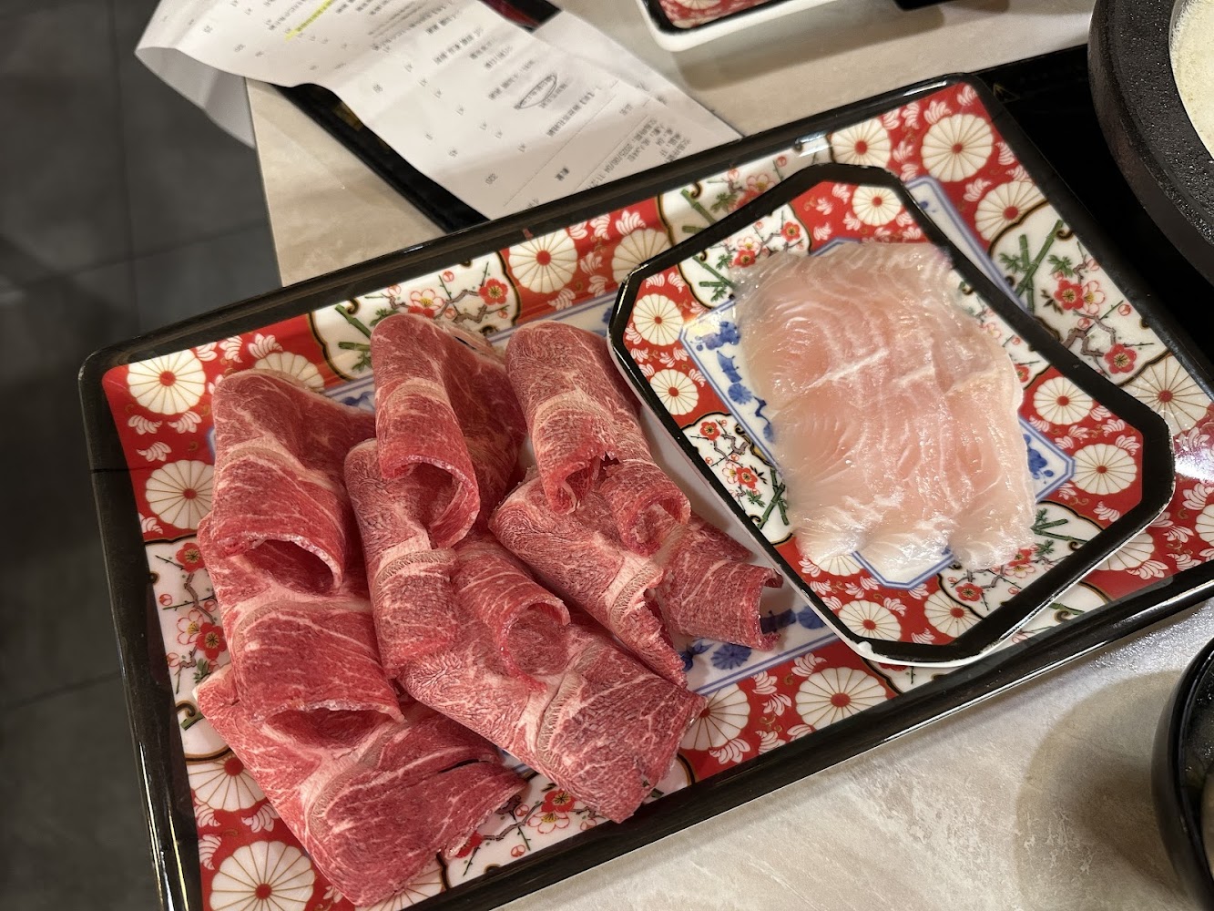 紅色牛肉片與白色海鮮食材放在精美盤中的近拍