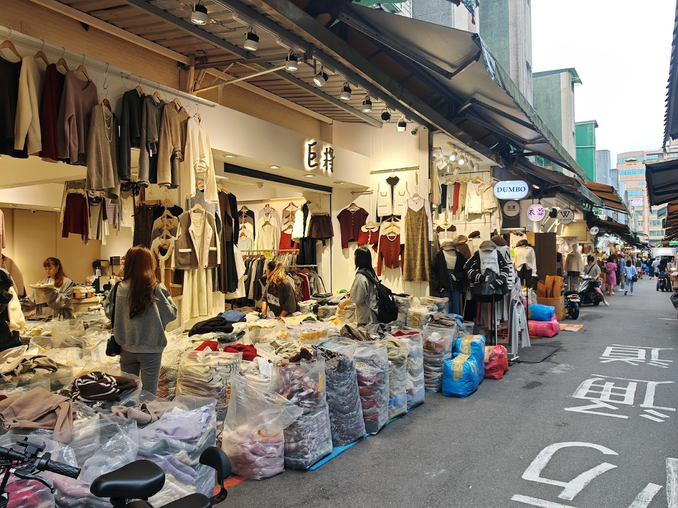 五分埔服飾商店街，衣服懸掛陳列、現場氣氛熱鬧。