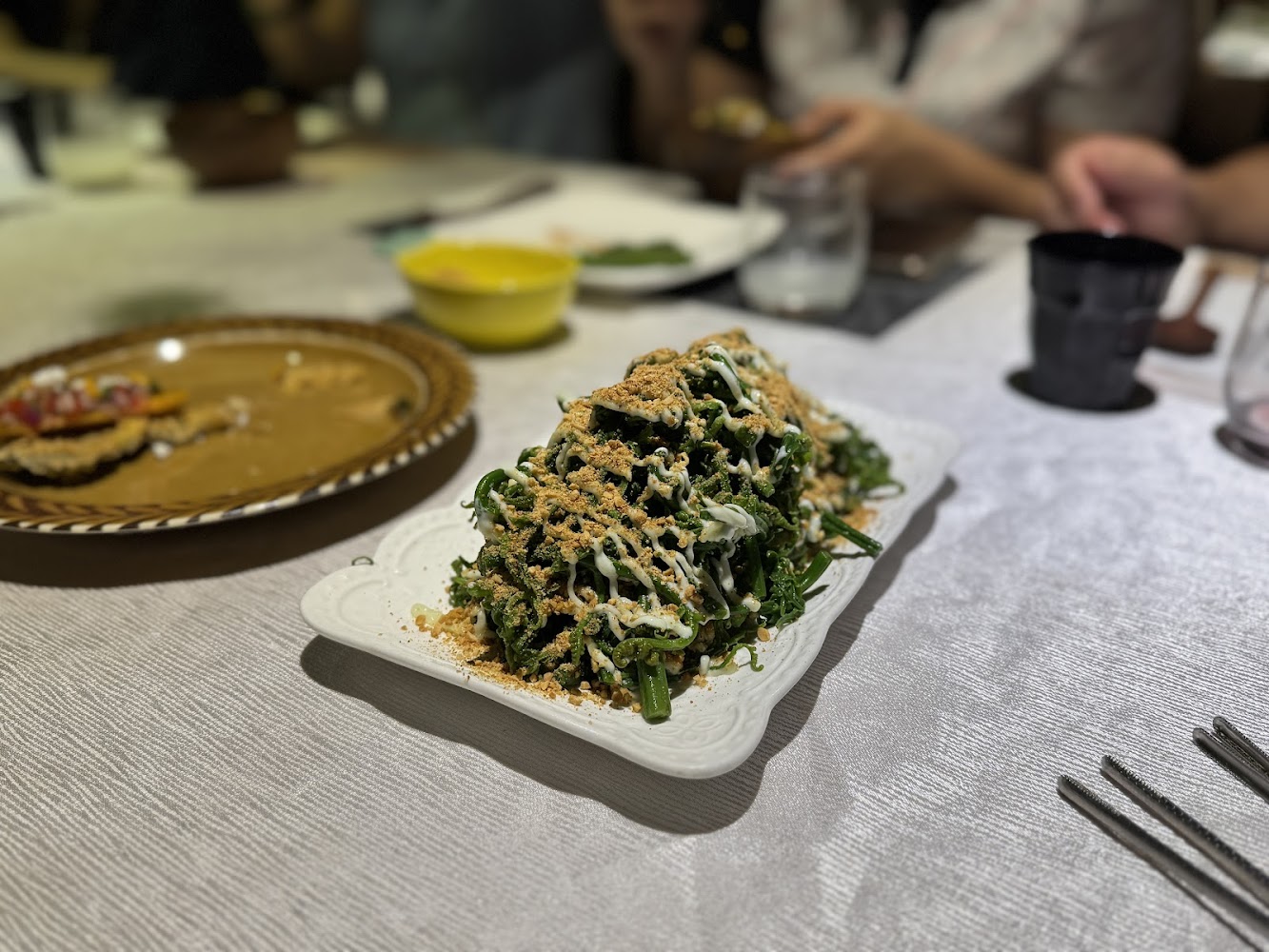 桌上擺放一盤蔬菜沙拉，撒有醬料與粉狀配料，呈現聚餐氛圍