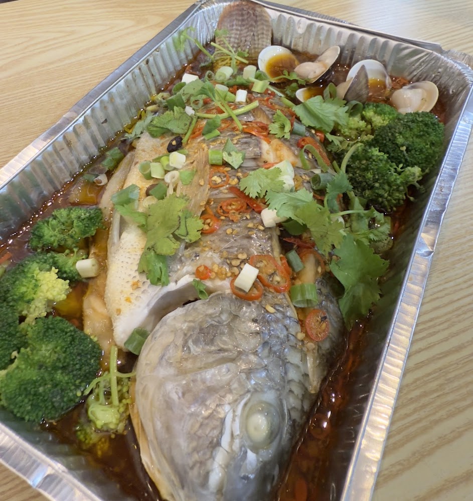 金枝玉葉夯魚的清蒸魚放在鋁箔盒中，搭配蛤蜊與香菜蔥花