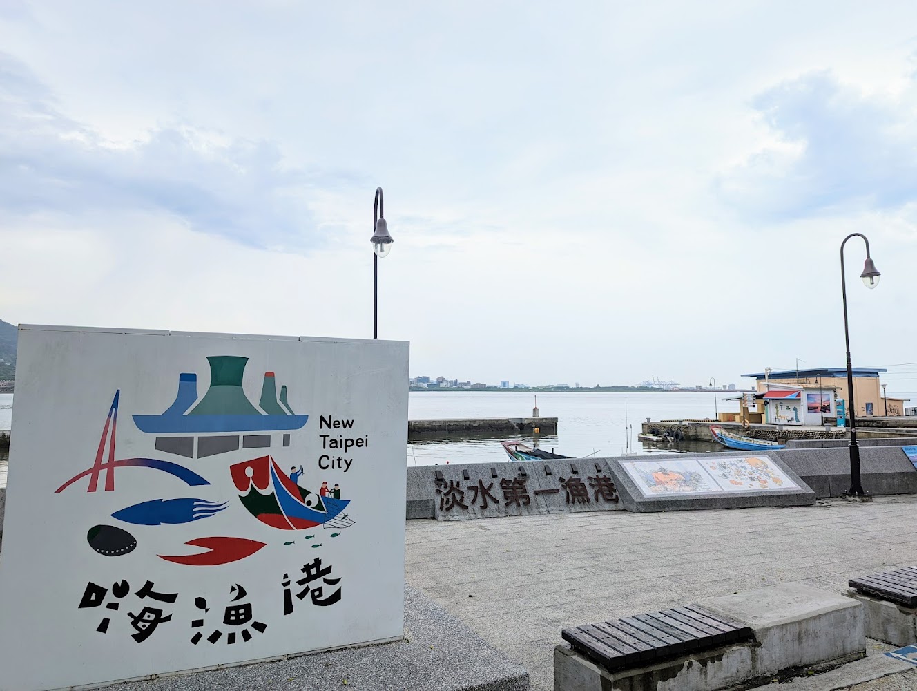 拍攝於新北市淡水漁人碼頭附近，可見淡水第一漁港招牌、船隻與海面
