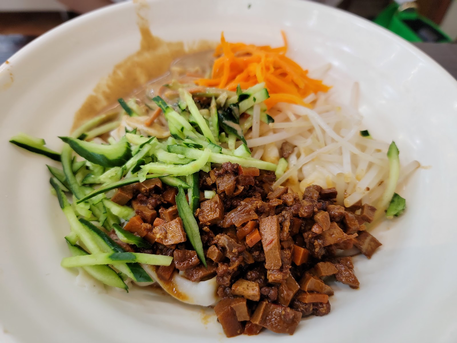 十一街炸醬手桿麵，白盤盛放麵條，配料有炸醬肉末、黃瓜絲、胡蘿蔔絲、豆芽
