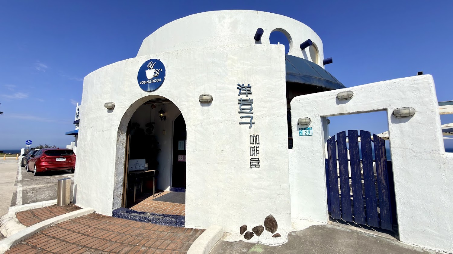 白色外觀的咖啡館,帶有地中海風格與藍色大門