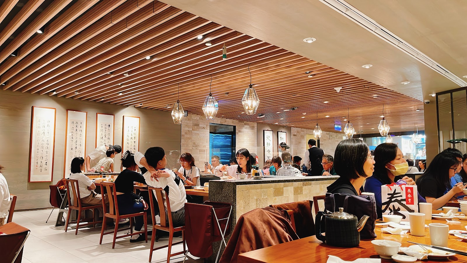 台北101購物中心中式餐廳，木條板天花板，菱形吊燈，牆面書法裝飾，顧客用餐
