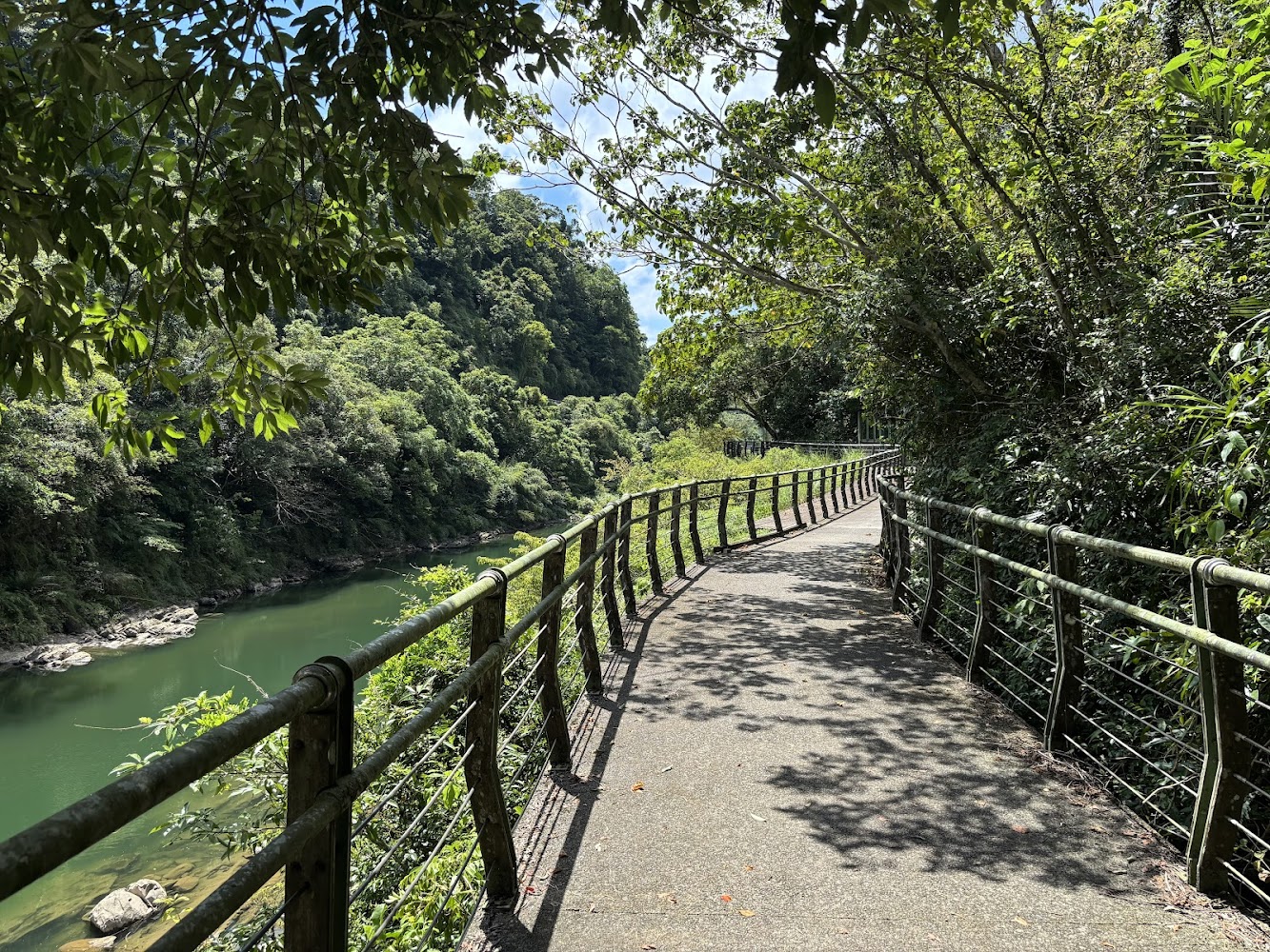 沿河岸而行的北勢溪自行車道,步道有護欄與綠樹包圍