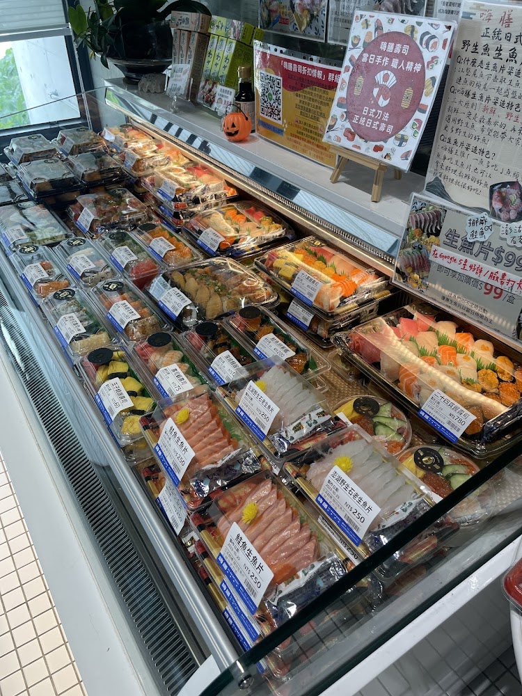 冷藏櫃中擺放各式壽司、刺身與壽司便當，包裝整齊標有價格