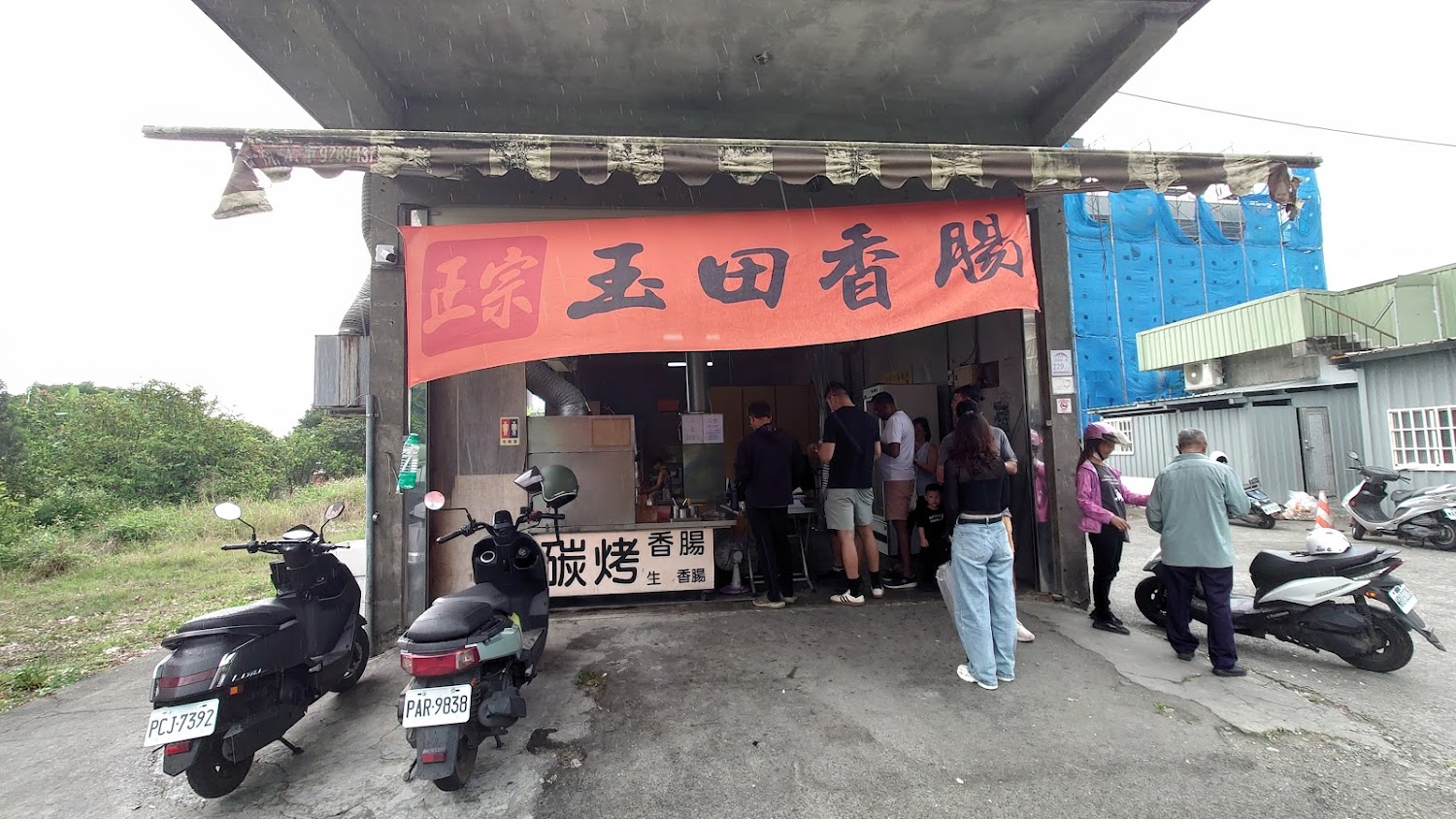 玉田炭烤香腸本店門口熱鬧排隊與機車停放景象