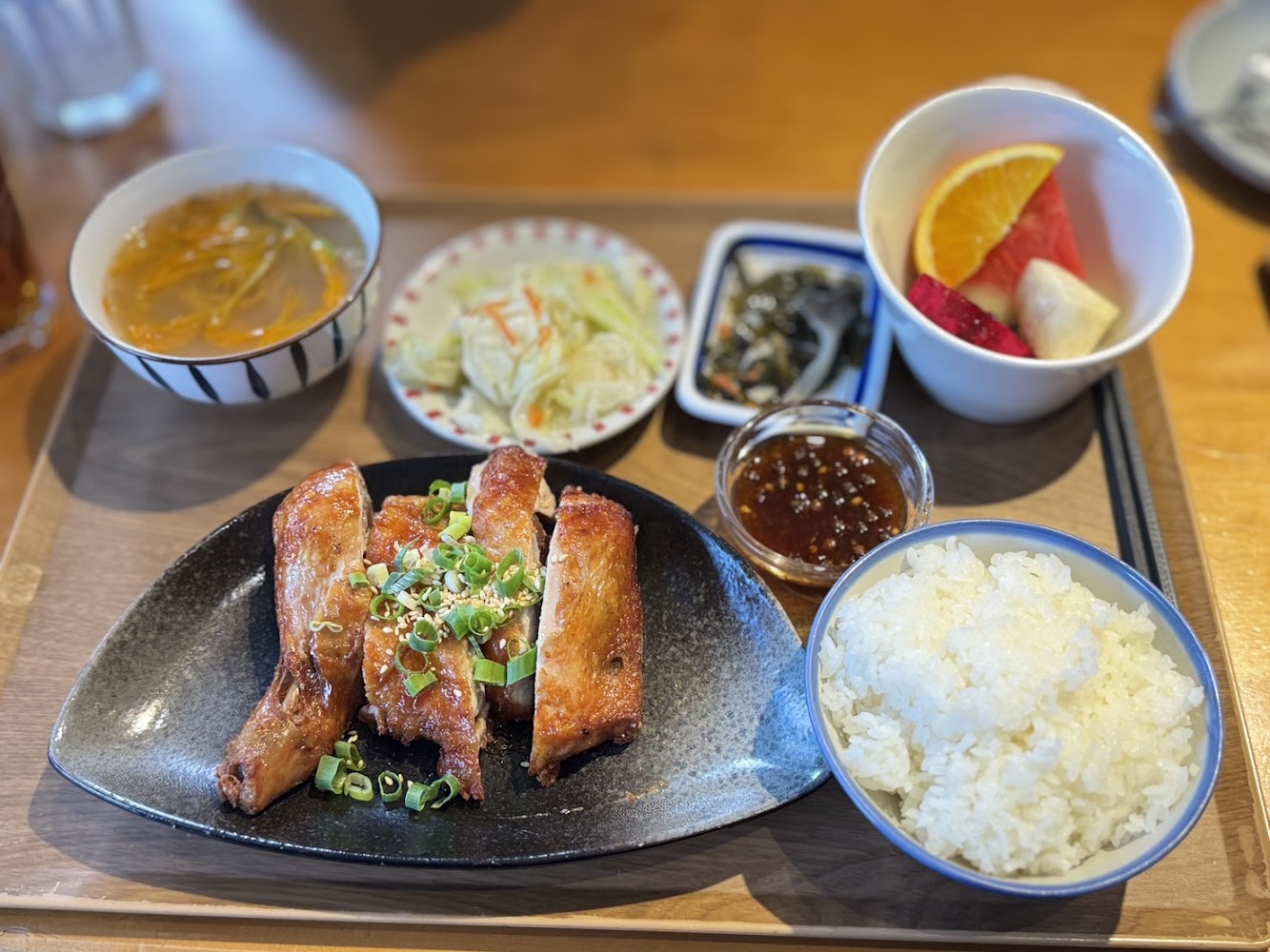 日式定食有烤雞腿肉、白飯、湯品、小菜和水果