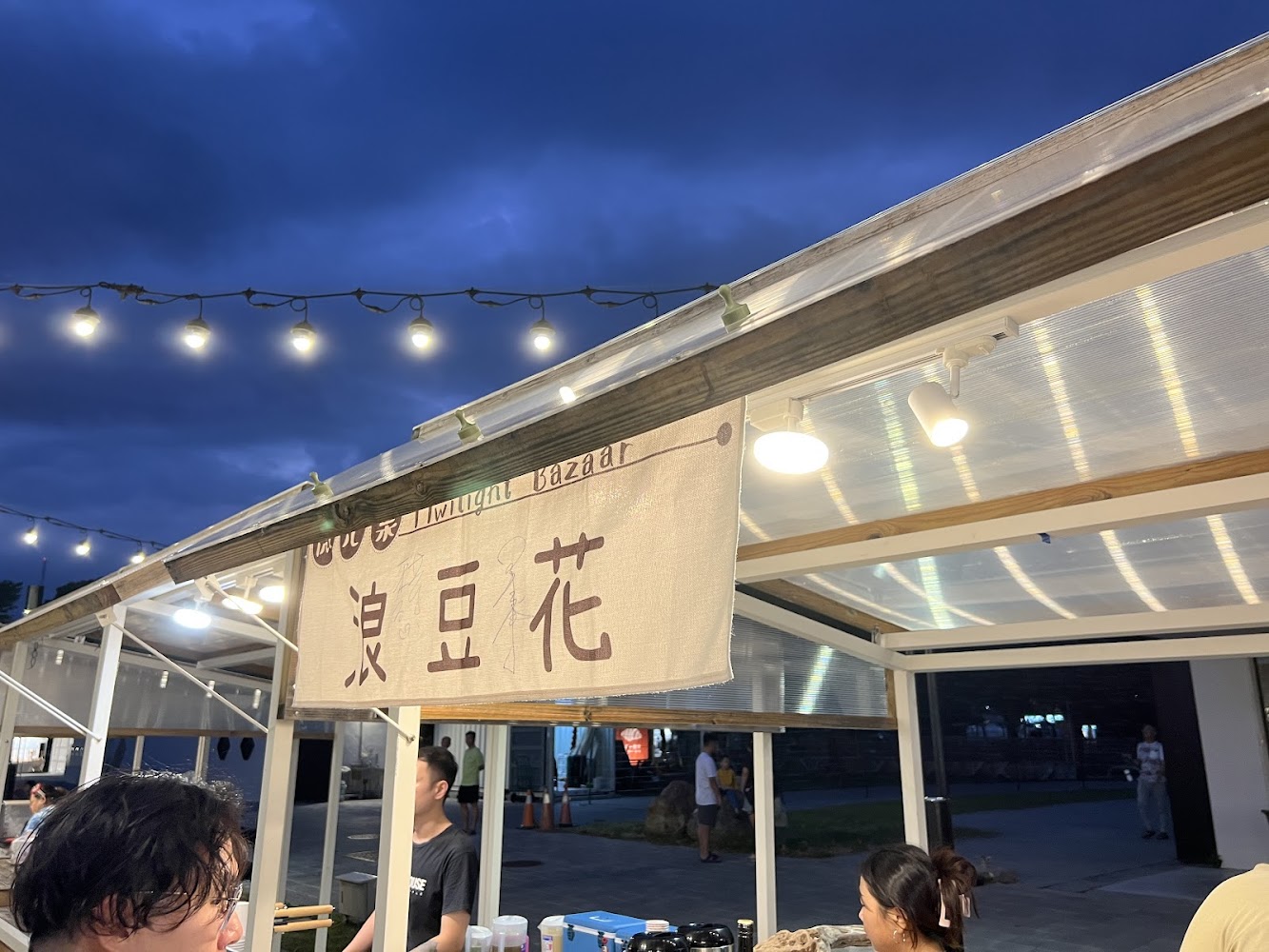 凍豆花攤位掛著串燈，有顧客排隊購買