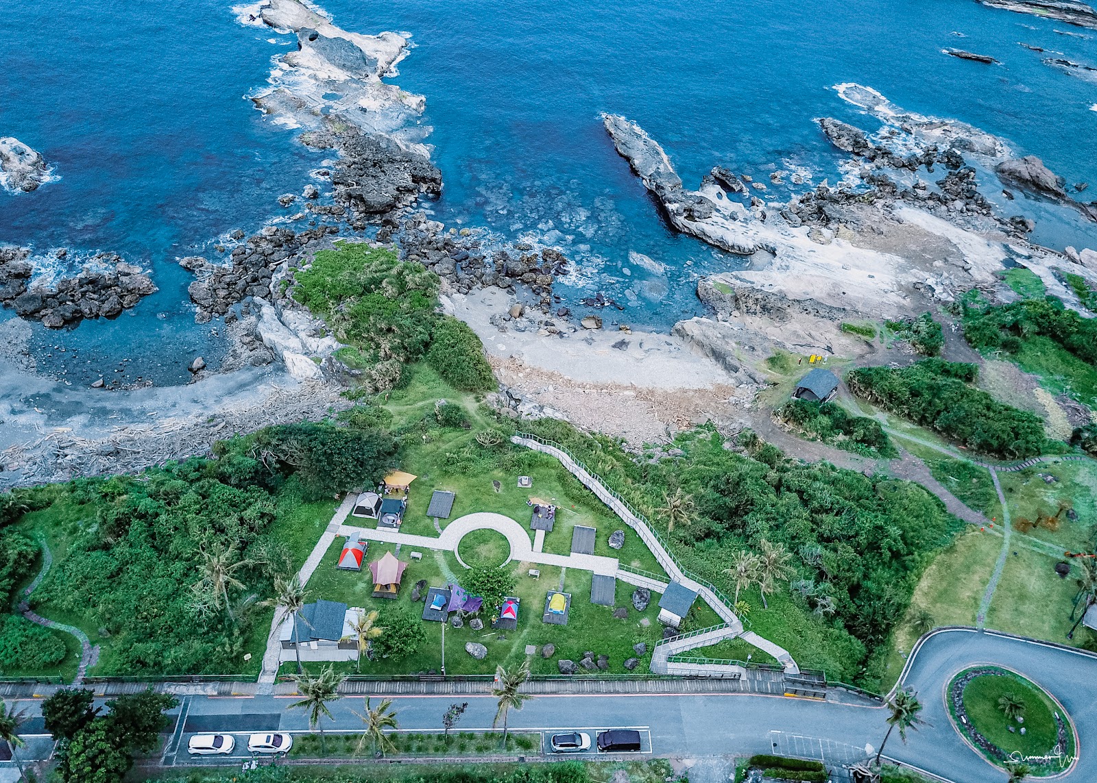 石梯坪空拍鳥瞰，草地露營區、礁岩地形與深藍太平洋同框