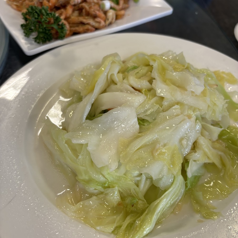 一盤清炒高麗菜色澤鮮亮，背景可見其他配菜