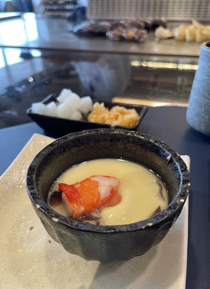 日式茶碗蒸上有蟹肉棒與香菇，後方有配菜