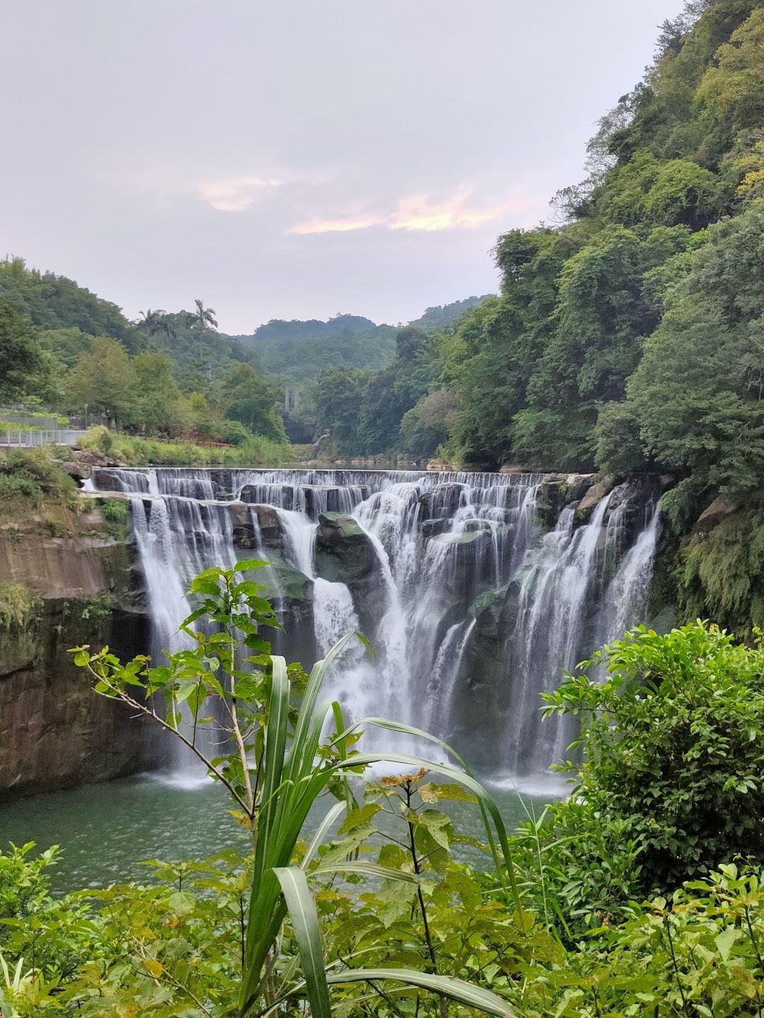 十分瀑布黃昏景色，多道水流，前景植物灌木，淡紫天空