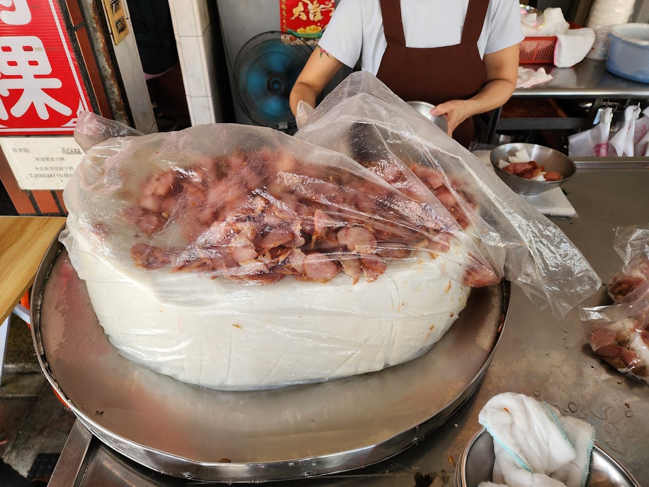 傳統台灣米糕表面鋪滿切片滷肉，後方有人員備餐