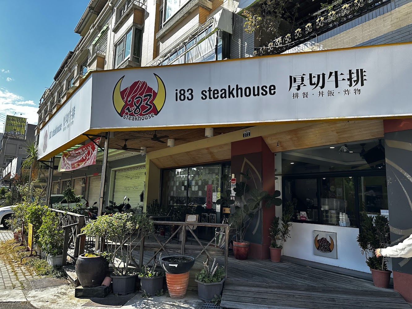i83厚切牛排店門口外觀有招牌戶外座位與植栽