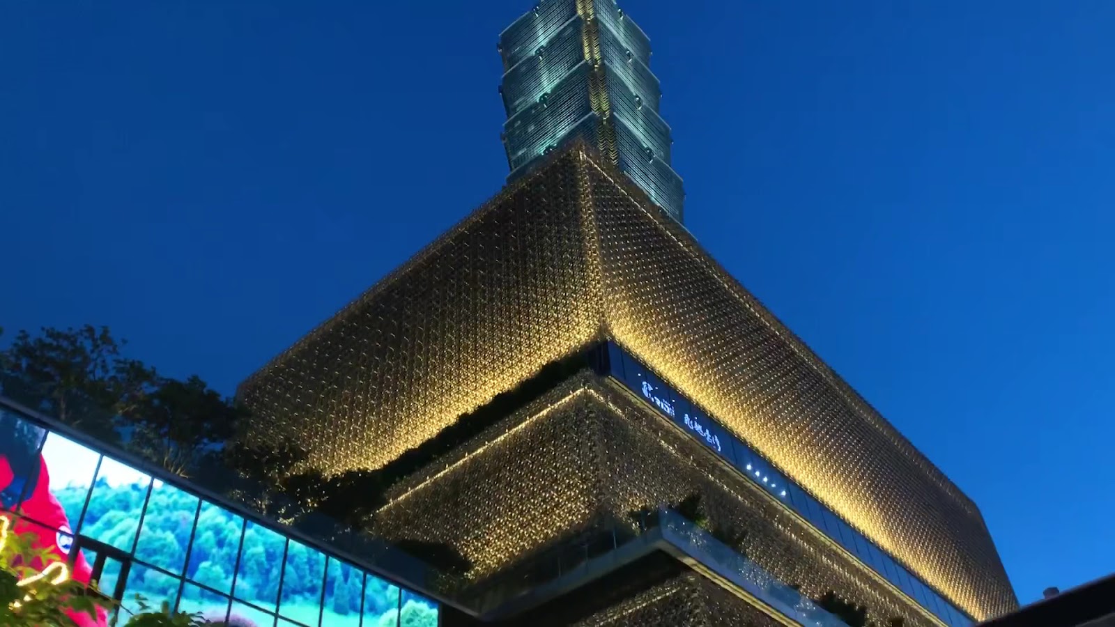 微風南山夜間建築外觀金色格紋外牆燈光，背景台北101信義區夜景
