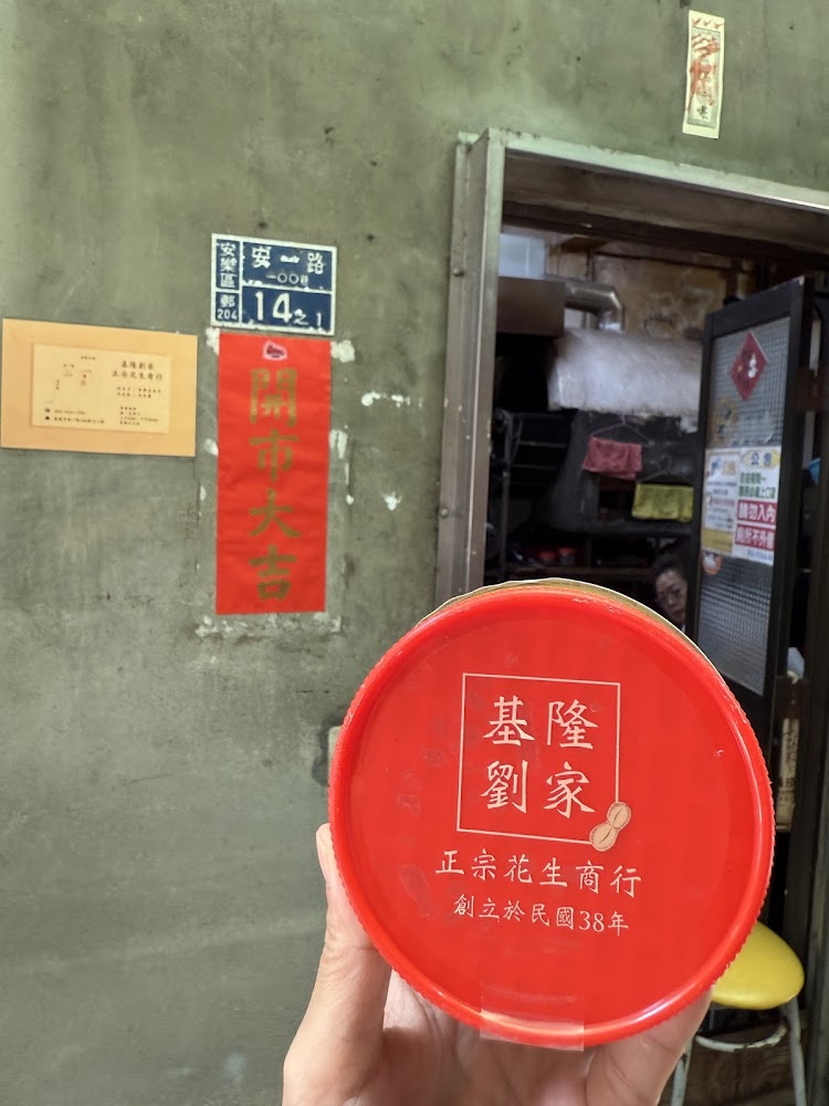 手持紅蓋花生產品與老屋門口背景