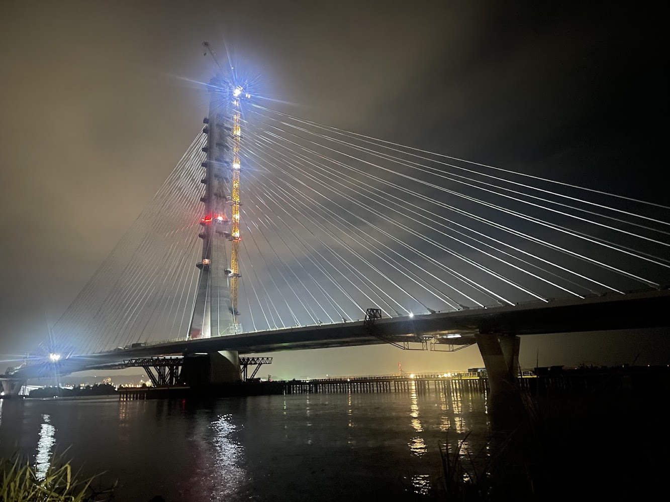 夜晚亮燈的大型斜張橋,橋塔高聳,拉索連接橋面並倒映水面