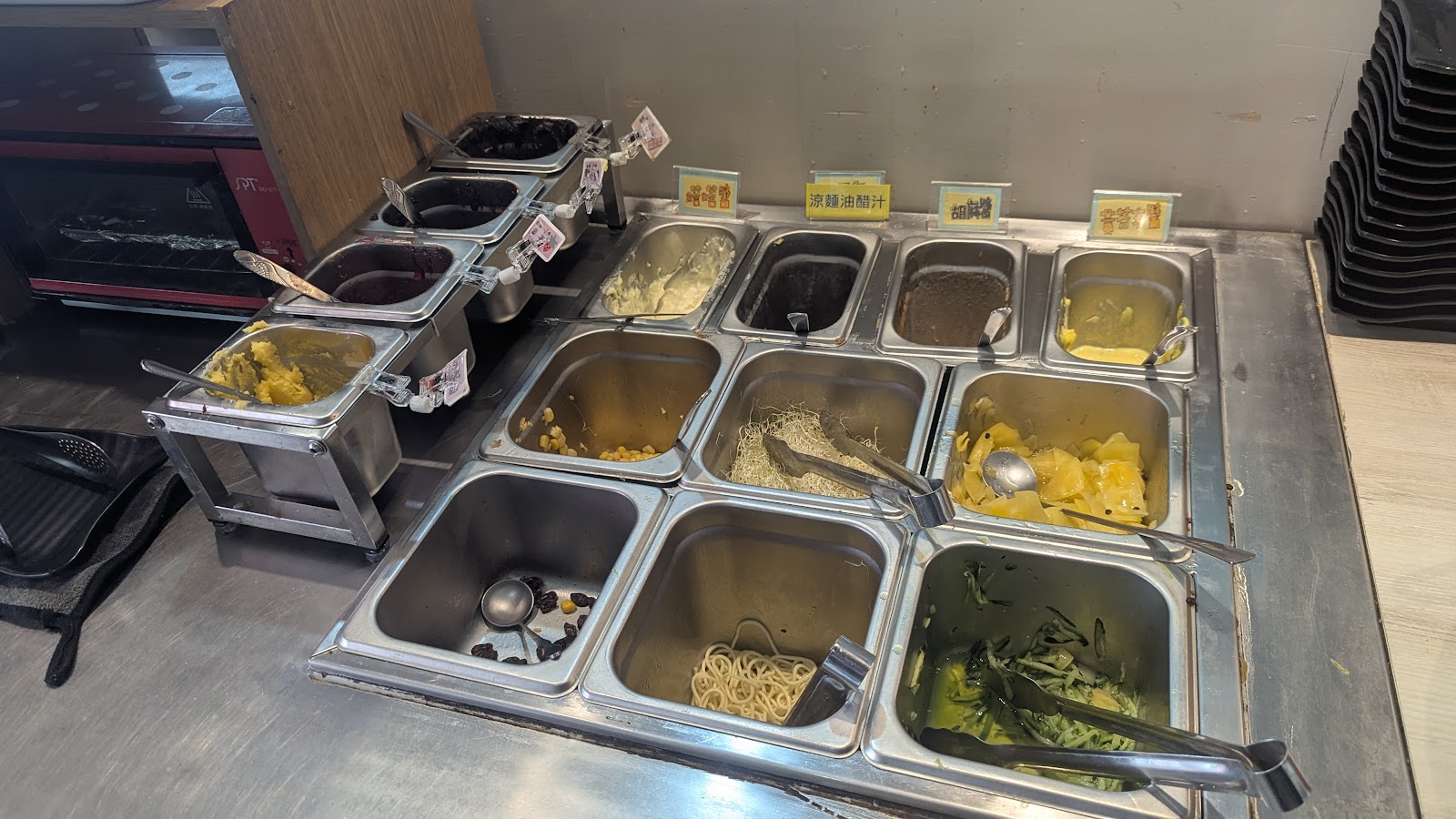 誠石火鍋西螺店自助醬料吧台，多格不鏽鋼容器排列整齊