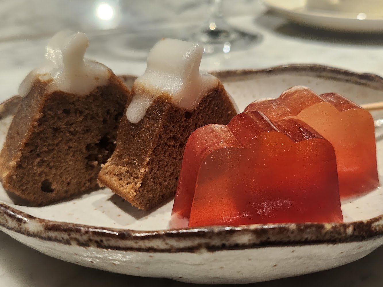 陶瓷盤內甜點包含糖霜小蛋糕與橙紅色果凍，造型可愛