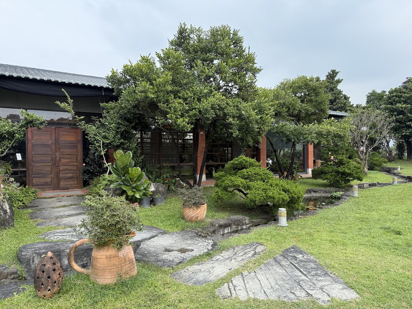 被綠意包圍的建築與庭院石板步道，各種植物盆栽營造寧靜氛圍