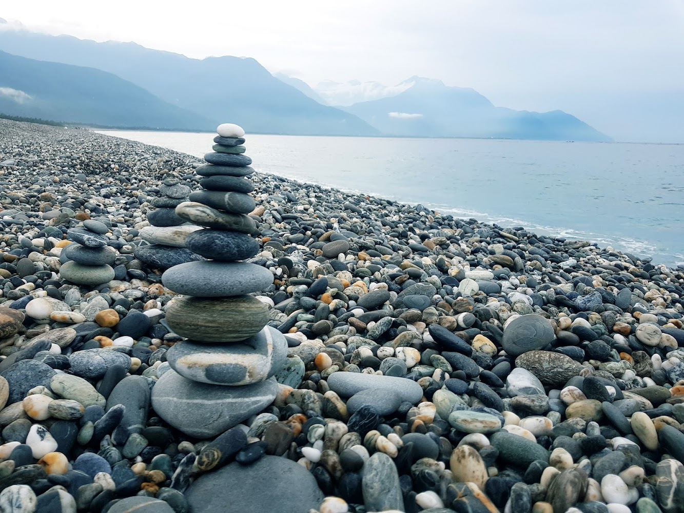 鵝卵石堆疊石塔與遠方海洋山脈景色